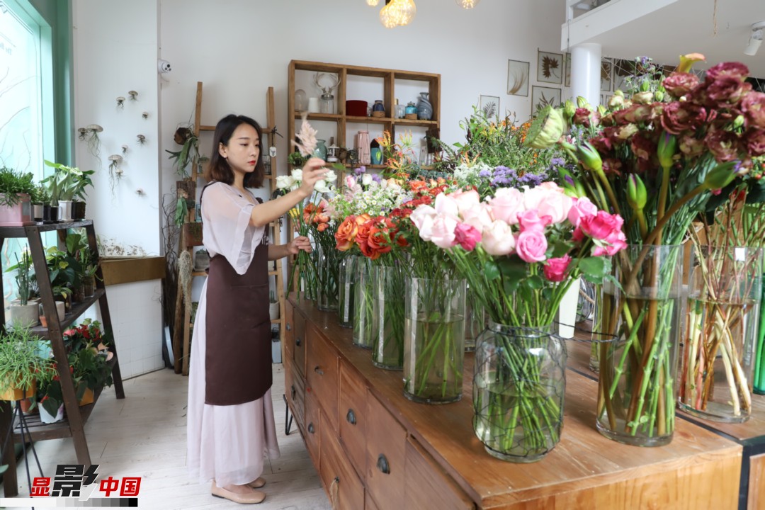 王黎媛是一名河南姑娘，在昆明念完大學后，就再也舍不下春城的藍天陽光、青山碧水，更舍不下這里的四時繁花，于是就干脆留了下來，成了一名媒體人。2017年的時候又毅然辭去工作，創(chuàng)業(yè)開起了花店，成了都市里的一名“花房姑娘”。圖為王黎媛在自己的花店中整理鮮花。新華網(wǎng) 周亞平/攝 念新洪/文